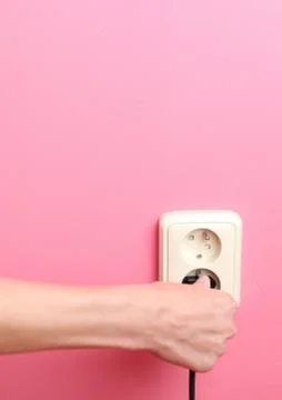 Young woman's hand plugging a power plug into an electric wall s Foto stock