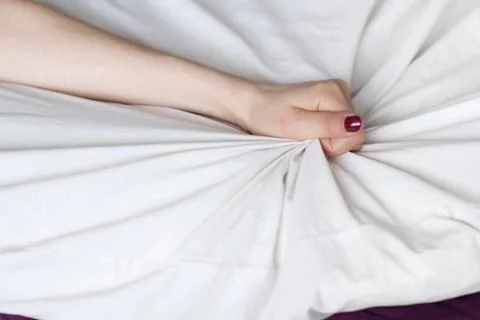 Young woman's hand squeezing white sheets Stock Photos