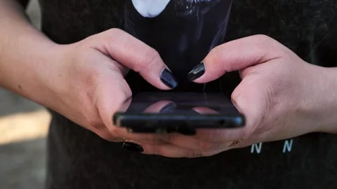A young woman's hand using a mobile phone, texting, and browsing the internet Stock Footage 334723244