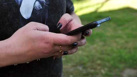 A young woman's hand using a mobile phone, texting, and browsing the internet Stock Footage 334723275