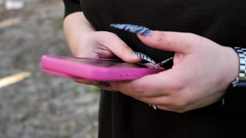 A young woman's hand using a mobile phone, texting, and browsing the internet Stock Footage 334723380