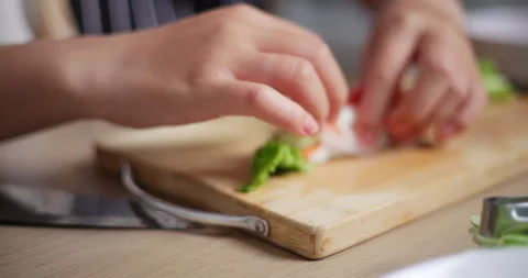 Young woman's hands carefully making salad rolls. Healthy home cooking.  Stockbeeldmateriaal 308346417
