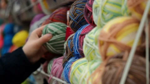 A young woman's hands choose the threads for knitting. Video stock 228999488