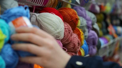 A young woman's hands choose the threads for knitting. Video stock 228999492