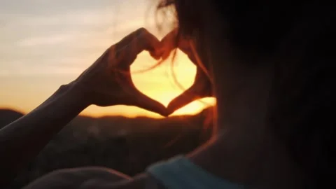 Young Woman's Hands Forming Heart Shape Framing Golden Sunset Stock Footage 345669524