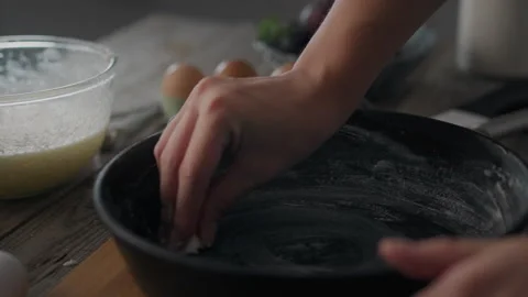 Young woman's hands holding baking mold and greasing it with butter. Dough, Stock Footage 250399061