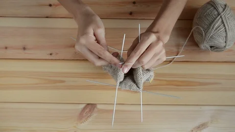 Young womans hands knitting with gray metal needles and woolen thread on wooden Stock Footage 121078487