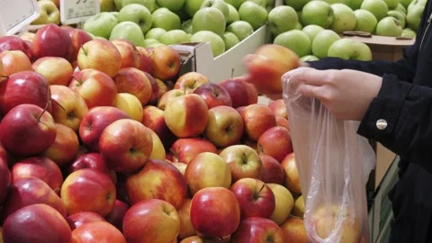 The young woman's hands put apples in a bag Stock Footage 232753569