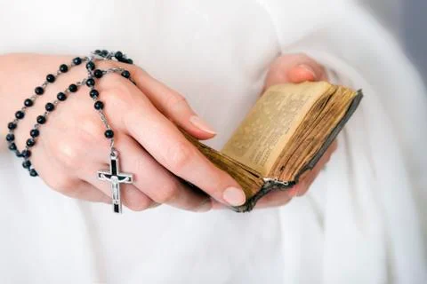 Young woman's hands with a rosary and a bible Stock Photos