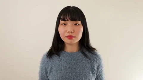 Young woman's shy smiling face. Asian. 20s. Dolly out. Slow-mo. Stock Footage 220699400