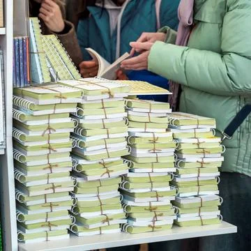 Young women and table with stack of books. Tall piles of various books stacked Stock Photos