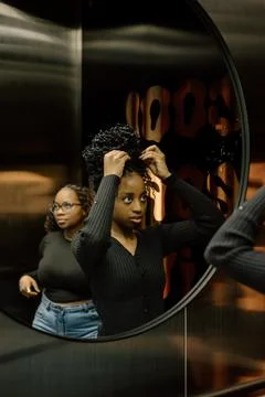 Young women in an elevator mirror reflection Stock Photos