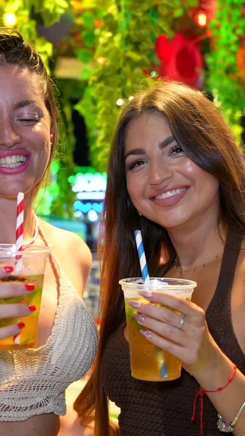 Young women enjoying refreshing drinks at a lively summer festival Stock Footage 313859608