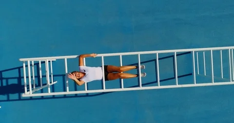 A young women pulls herself up onto Monkey Bars and waves at camera. 스톡 동영상 86137969