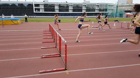 Young women running hurdles track and field. Slow motion. Stock Footage