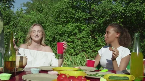 Young women sits at the table, eats vegetables, drinks and waits for bbq Stock Footage 143472142