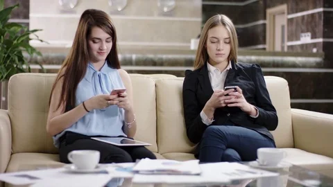 Young women sitting and using their smartphones Stock Footage