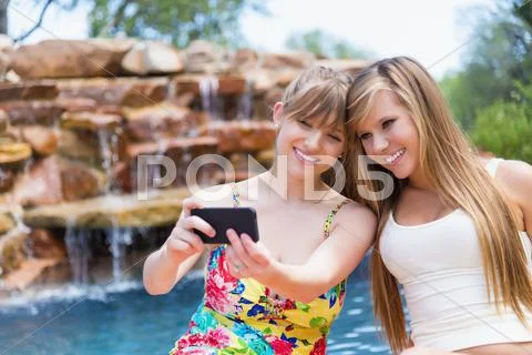Young Women Using Smart Phone To Take Picture At Swimmin Pool, Smiling