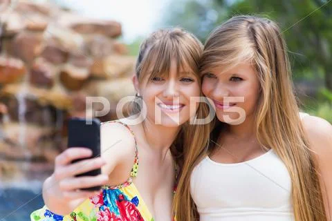 Young Women Using Smart Phone To Take Picture At Swimming Pool, Smiling