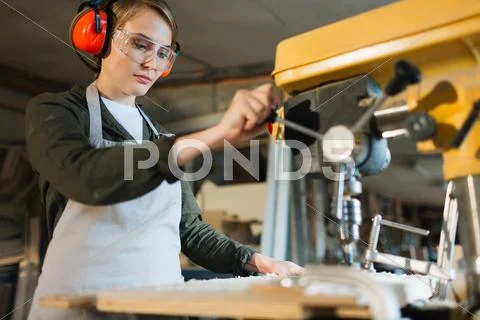 Young woodworker processing timber on special machine Stock Photos