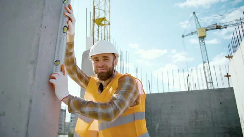 A young worker checks the level of the wall with a spirit level Stock Footage 241167439