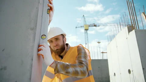 A young worker checks the level of the wall with a spirit level Stock-Footage 253585595