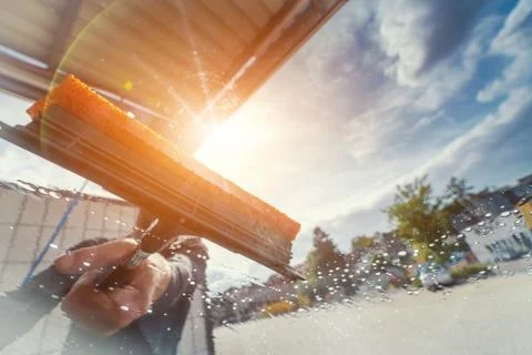 Young worker drying cars windshield at car wash. Stock Photos