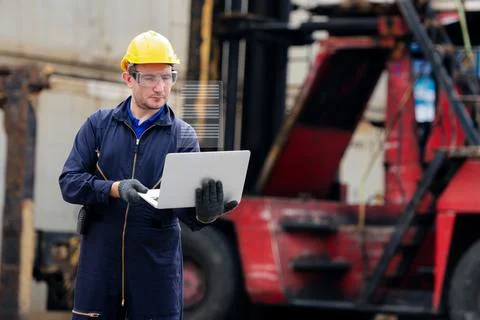 Young worker engineer wearing yellow safety hard hat using laptop computer la Stock Photos