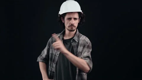 The young worker in the engineer's white helmet points with his finger to the Stock Footage 155088637