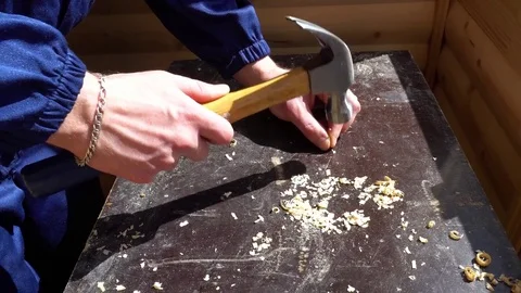 A young worker in the form of strikes with a hammer the nail into the table Stock-Footage 75210611