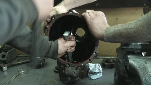Young worker hitting inside of a transmission case with a hammer in a workshop Stock-Footage 127337720