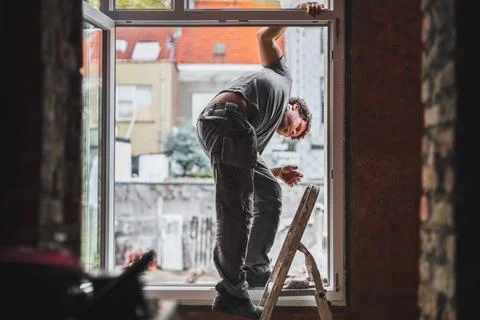 A young worker inspects window frames before repairs. Stock Photos