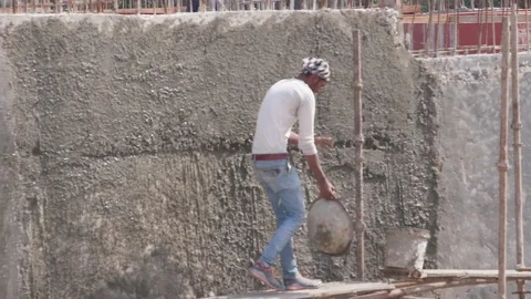 Young worker pouring cement in the vessel at a construction site Stock Footage 77447627