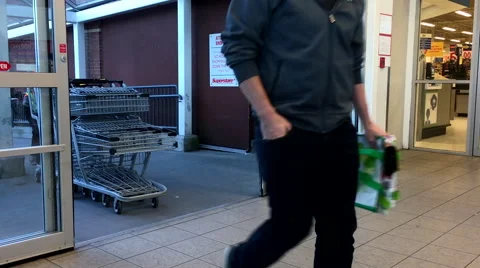 Young worker pushing trolleys walking through the doors at superstore Stock Footage 68514065