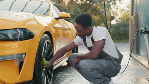 Young worker of self car wash service African bearded man cleaning a wheel, car 스톡 동영상 171679182