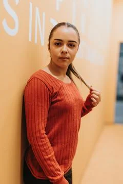 The young worker takes it easy, posing casually in the vibrant office setting. Stock Photos