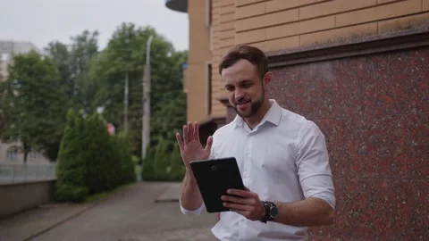 Young worker talks outdoor on his black tablet Video stock 157801407