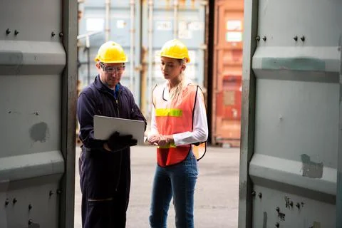 Young worker team with laptop at container terminal port warehouse for check  Stock Photos