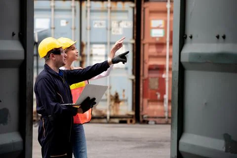 Young worker team with laptop at container terminal port warehouse for check  Stock Photos