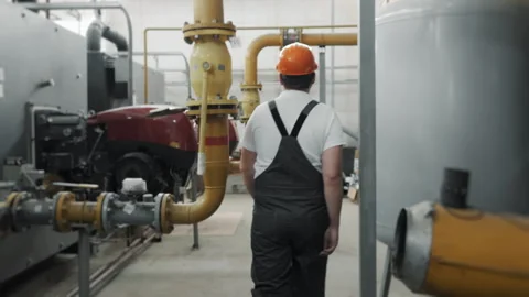 A young worker in a uniform walking through a factory. Stock Footage 306815084