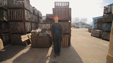 A young worker in uniform walks between wooden pallets in distribution outdoor 库存影片 112336825