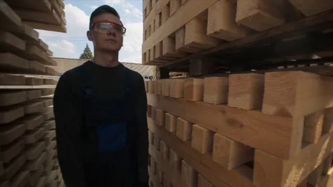 A young worker in uniform walks between wooden pallets in distribution outdoor 스톡 동영상 112336851
