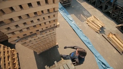 A young worker in uniform walks between wooden pallets in distribution outdoor Vídeo Stock 112336986