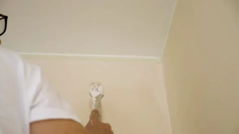 Young worker using the brush for corners to finish work - slow motion  Stock Footage 130699819