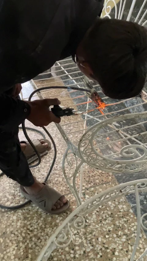A young worker is welding an old metallic chair in slow motion. Stock Footage 340410986