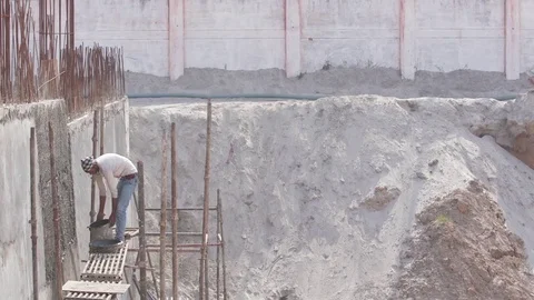 Young worker wetting the newly cemented wall at a construction site Stock Footage 77447699