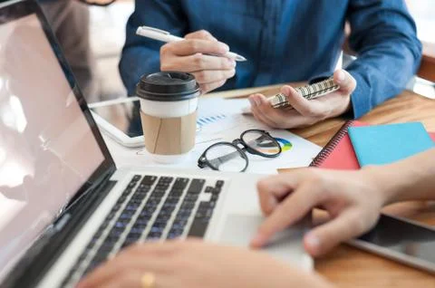 Young worker writing on notebbok while working with colleague Stock Photos