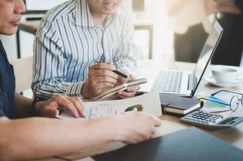Young worker writing on notebbok while working with colleague Stock Photos
