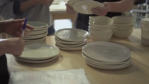 Young workers is looking at plates in ceramic workshop. Stock Footage 87333526