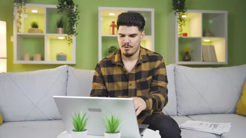 Young working between documents and laptop finishes his work and relaxes. Stock Footage 237348949